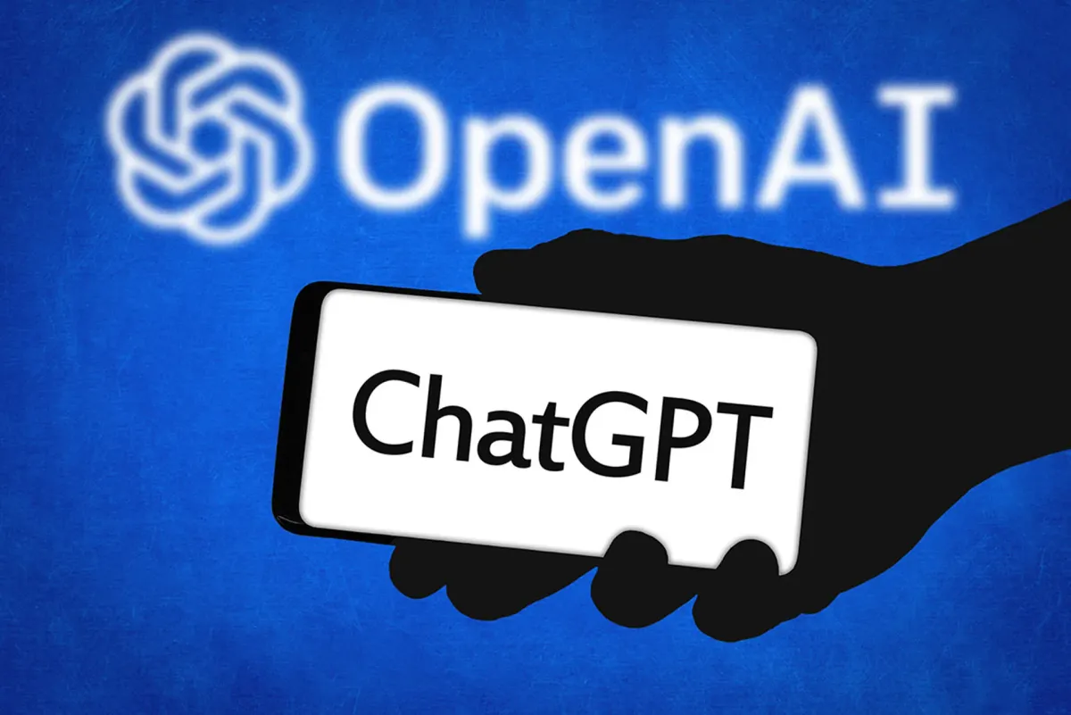Một bàn tay đang cầm điện thoại hiển thị 'ChatGPT' trên nền logo OpenAI màu xanh.